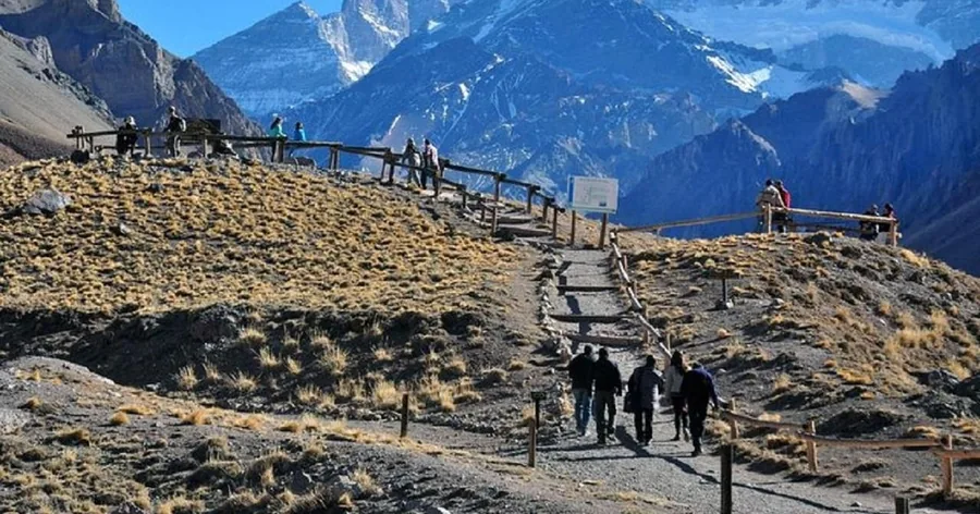 Visitors on the gravel path and wooden boardwalk to the Horcones lagoon viewpoint, the mountain behind